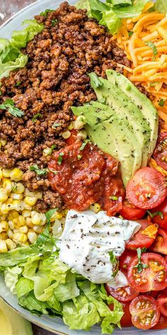 a plate with pasta, lettuce, tomatoes, corn and avocado