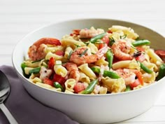 a bowl filled with pasta and shrimp on top of a table next to a fork