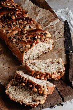 sliced loaf of bread sitting on top of a wooden cutting board next to a knife