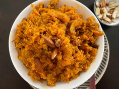 a white bowl filled with carrots and nuts next to another bowl full of almonds