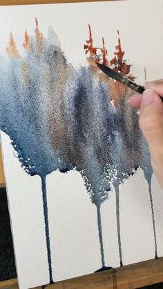 someone is painting trees with watercolors on paper