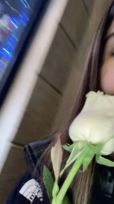 a woman holding a white rose in her right hand and looking up at the camera