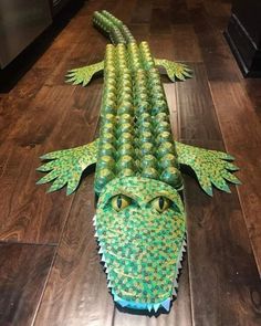 an alligator made out of paper sitting on top of a wooden floor