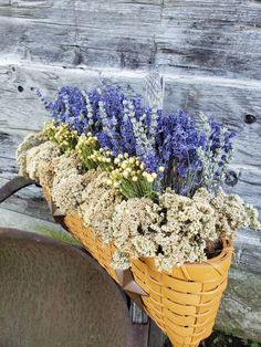 a basket filled with flowers sitting on top of a wooden bench