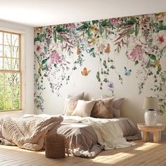 a bed sitting in a bedroom next to a window with flowers on the wall behind it