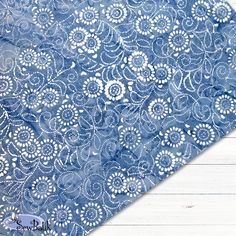 a blue and white table cloth with an intricate design on it, sitting on a wooden surface