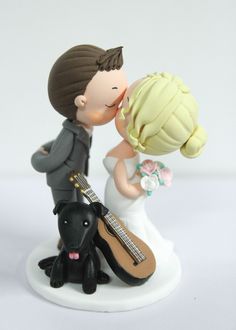 a wedding cake topper with a bride and groom kissing next to a black dog