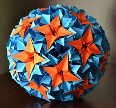 an origami ball on a table with orange and blue stars in the middle