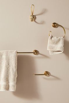 two towels hanging on the wall next to gold hooks and towel racks with white towels