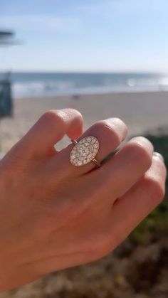 a woman's hand holding a diamond ring on the beach