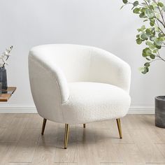 a white chair sitting on top of a wooden floor next to a potted plant