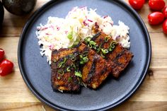 two pieces of meat and rice on a black plate