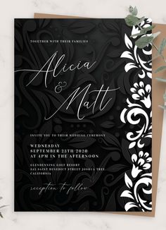 an elegant black and white wedding card with floral design on the front, in gold foil