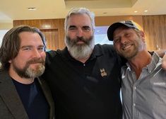 three men are posing for the camera with one pointing at the camera and the other smiling