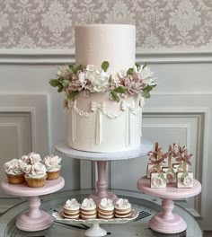 three tiered wedding cake and cupcakes on display