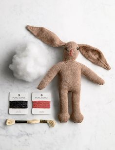 a stuffed animal next to some sewing supplies on a white counter top with cotton balls