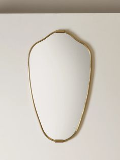 a mirror hanging on the wall in a room with white walls and gold trimmings