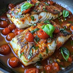 two fish with tomatoes and basil in a pan