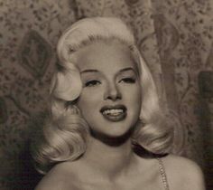 an old photo of a woman with blonde hair and pearls on her head, wearing a beaded dress