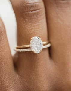 a woman's hand with a diamond ring on top of her finger and an engagement band