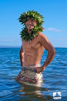 a man standing in the water wearing a wreath on his head