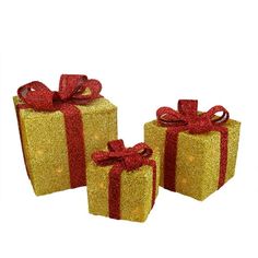 three gold gift boxes with red bows and lights on them, all wrapped in glitter