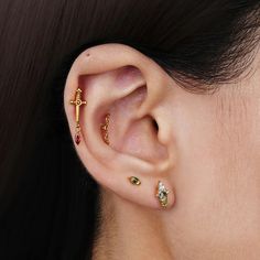 a close up of a person's ear with three different colored stones on it