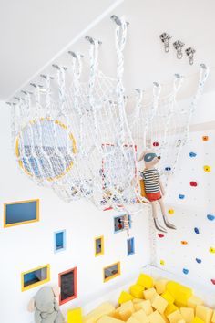 a child's play area with climbing ropes, toys and pictures on the wall