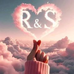 a person holding up a pink heart above clouds with the word r & s written on it