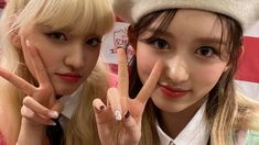 two young women making the peace sign with their fingers in front of an american flag