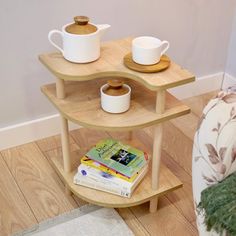 two wooden shelves with cups and books on them in the corner of a living room