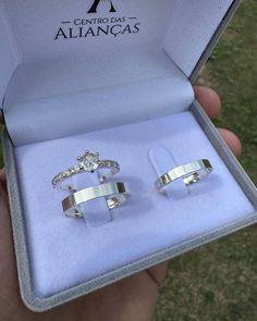 two silver rings are in a box on the grass, one is open and the other is closed