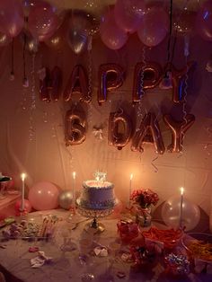 a birthday cake surrounded by balloons and confetti on a table with other decorations