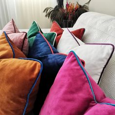 a bunch of pillows sitting on top of a couch next to a vase with flowers