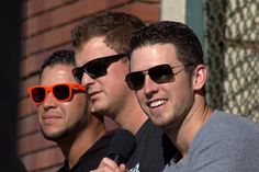 three men wearing sunglasses are standing next to each other and one is holding a microphone