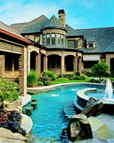 a large house with a fountain in the front yard and landscaping around it, as well as an outdoor swimming pool