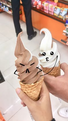 a person holding an ice cream cone with faces drawn on it in front of a store