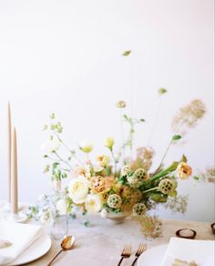 the table is set with plates, silverware and flowers in a vase on it