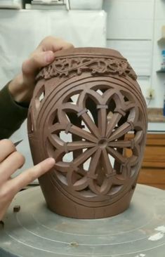 a person is making a vase out of clay