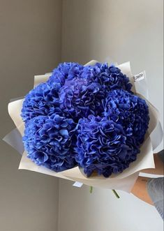 a bouquet of blue flowers sitting on top of a white paper wrapped in wax paper