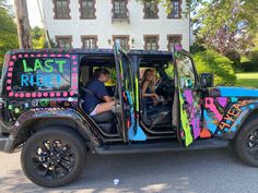 a man and woman sitting in the driver's seat of a decorated jeep