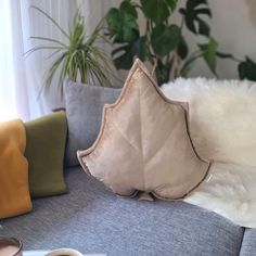 a pillow sitting on top of a couch next to a plant