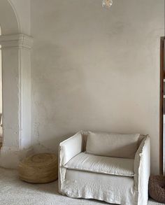 a living room with a white couch and chair next to a lamp hanging from the ceiling