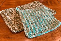 two crocheted dishcloths sitting on top of a wooden table