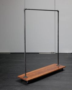 a wooden shelf with two metal bars on it and a white wall in the background