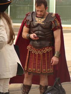 a man dressed as a roman soldier looking at his cell phone