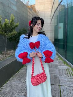 a woman in a white dress holding a red and blue purse