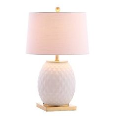 a white table lamp with a gold base and a light shade on the top of it