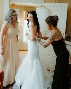 two women in dresses are helping another woman get ready for her big day at the wedding