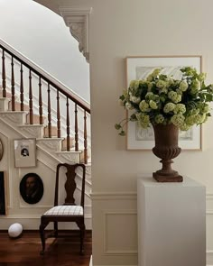 a vase filled with flowers sitting on top of a table next to a stair case